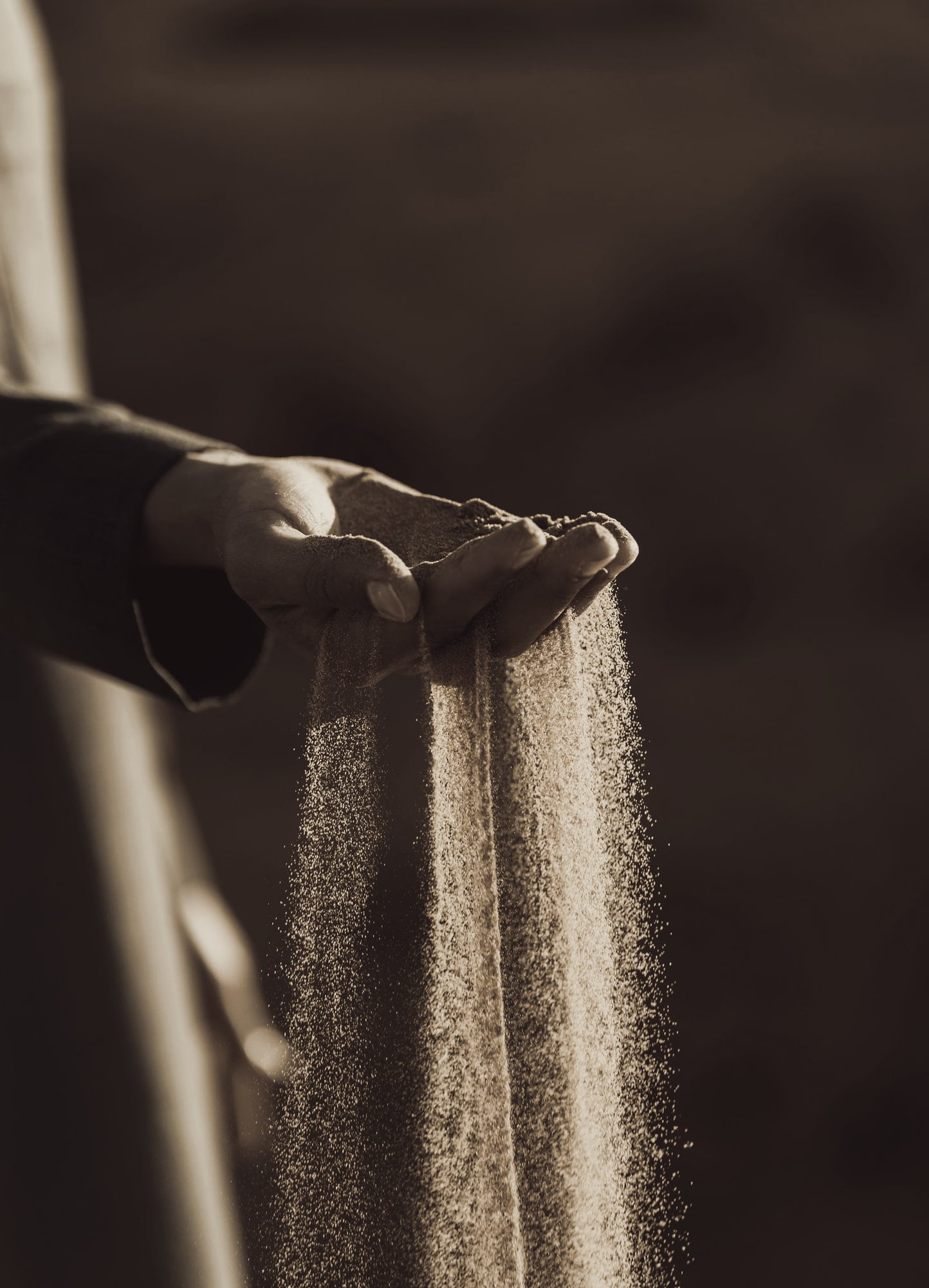 Une main laisse filer du sable entre ses doigts
