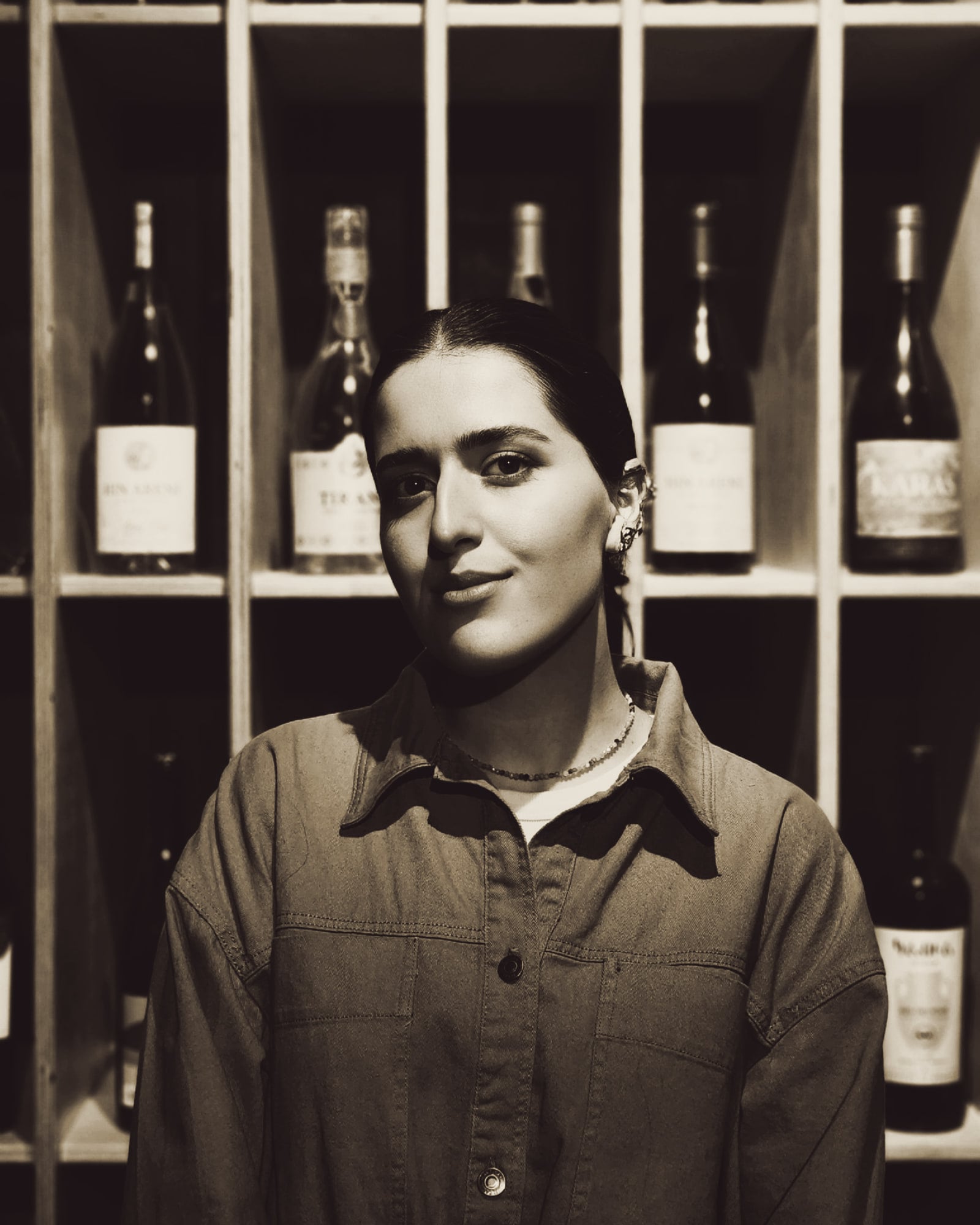 Portrait de Jeanne Deniau devant les casiers à bouteilles du caveau